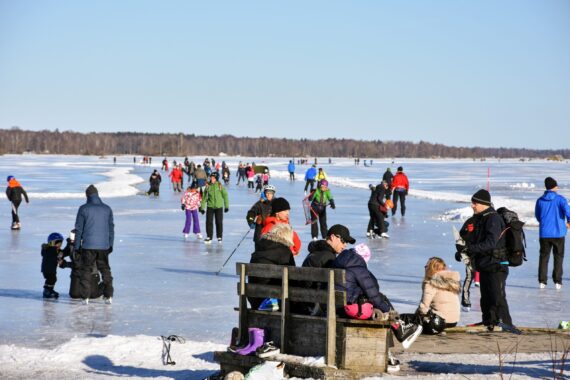 Många personer njuter av en fin dag på skridskoisen.